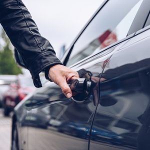 Man is reaching for the car door handle. Car rental or car theft concept