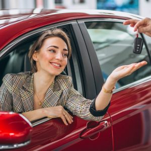 Woman sitting in red car and receiving keys